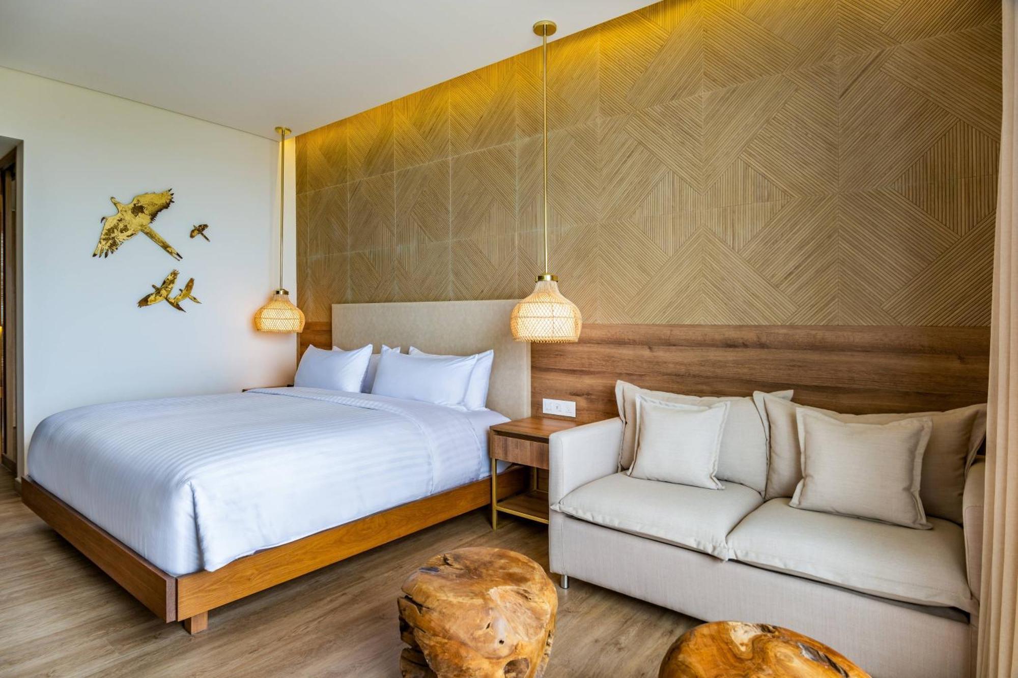 Habitación con 1 cama extragrande, sofá cama, balcón y vistas parciales al mar